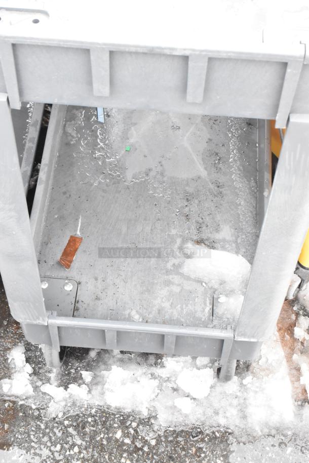 Gray 2-tier poly cart on commercial casters, showing surface wear and outdoor usage on snowy pavement.