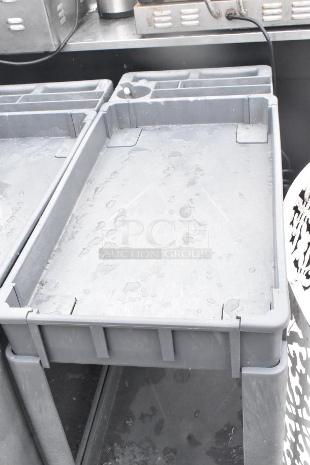 2 Poly 2-Tier Cart on commercial casters, gray, used condition, sturdy design, water droplets on surface, industrial setting.