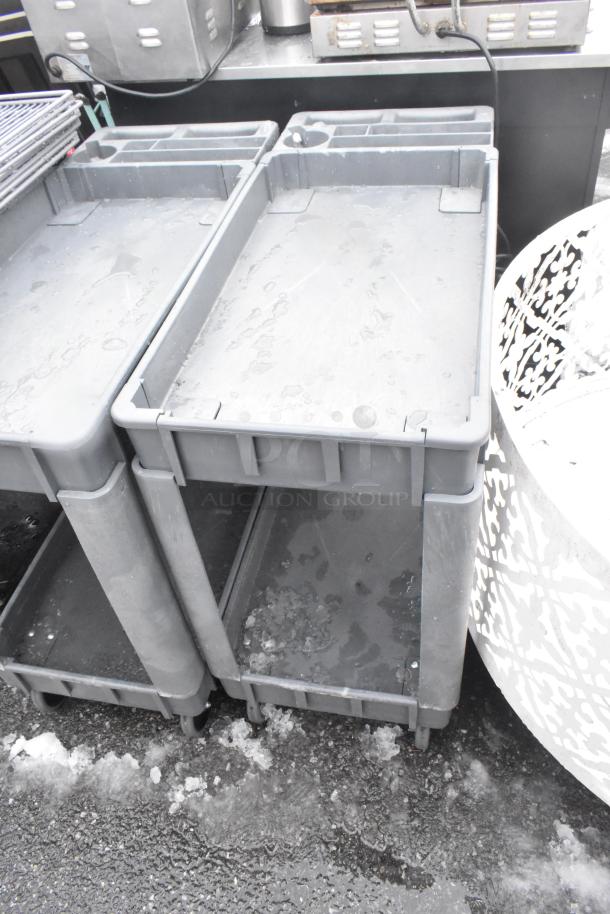 2 Poly 2 Tier Carts with commercial casters, gray color, showing light wear, ideal for heavy-duty use and mobility.