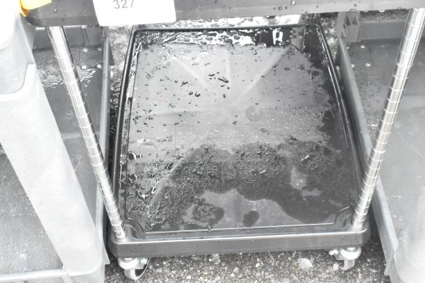 Black 2-tier cart on commercial casters, containing wire racks; slight wear visible, sturdy metal frame.