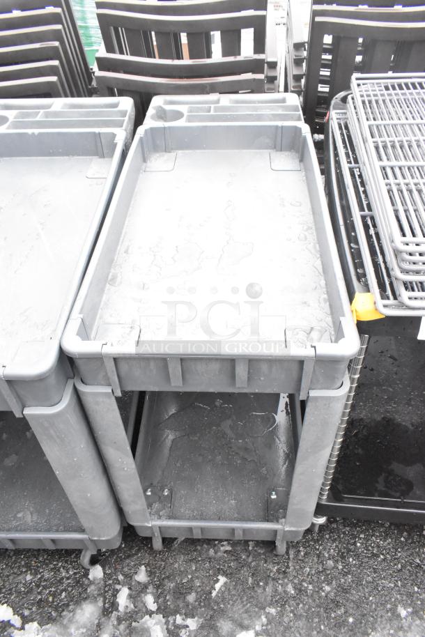 Gray 2-tier poly cart on commercial casters, showing signs of use. Ideal for industrial storage and transport.