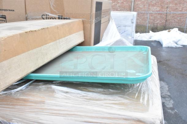 Stack of auction items including Rubbermaid Slim Jim trash can boxes, plastic trays, and wrapped packages in outdoor setting.