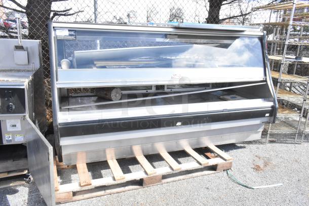 Commercial floor-style warming display case merchandiser, stainless steel, glass front, dual-shelf, used condition, on pallet.