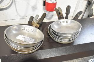11 skillets, metal, used condition, two stacks with non-stick surfaces. Auction label reads "55 QTY x11."