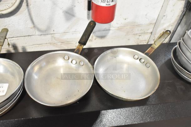 Set of 11 aluminum skillets with riveted handles. Used condition, slight wear visible. Ideal for bulk purchase.