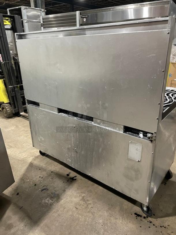 Southbend stainless steel gas range and double oven combo, 6 burners, flat griddle, with overhead shelf, on casters.