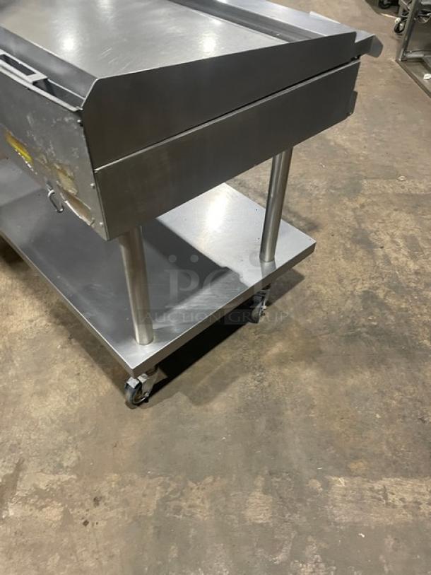 Vulcan stainless steel countertop flat top griddle on a stand with casters, features back & side splash, thermostatic control, natural gas powered.