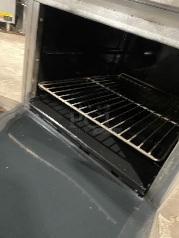American Range stainless steel gas 4-burner range/oven combo with backsplash, salamander shelf, and wired oven rack.