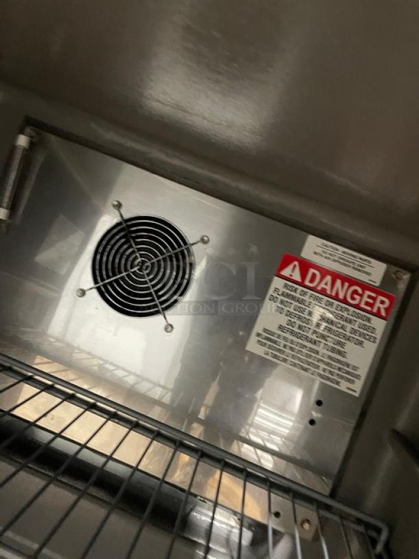 Delfield stainless steel undercounter refrigerator, model 406PSTAR2, with coated wired rack and safety label, interior view.