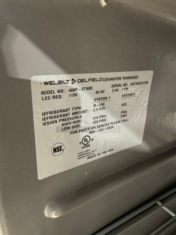 Delfield 406P-STAR2 stainless steel undercounter refrigerator, model 406P-STAR2. Includes coated wired rack, 27" worktop, 115V, 1-phase, on casters. Visible label shows specs and NSF certification.