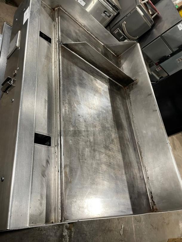 WoodStone commercial stainless steel gas-powered countertop split-top plancha flat griddle with back and side splash, on legs.