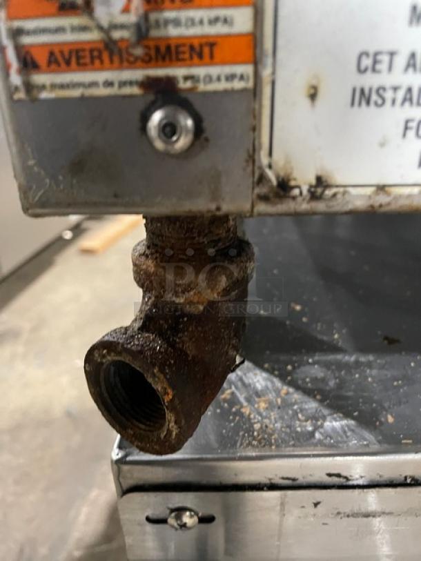 WoodStone Commercial Stainless Steel Gas Griddle with split-top, back and side splash, on legs. Some rust visible.