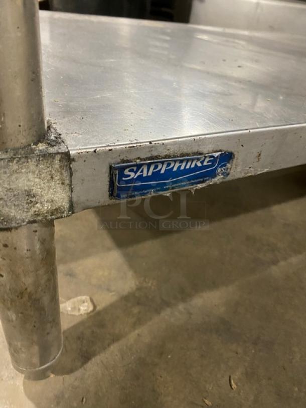 Sapphire stainless steel worktop table with undershelf, on legs, visible wear. Blue label with brand name on corner.