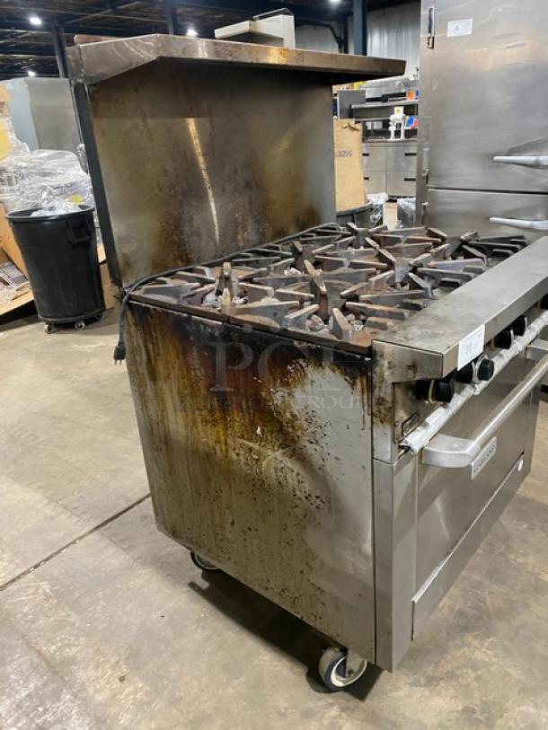 Garland G366C stainless steel 6-burner gas range/oven combo with backsplash, overhead salamander shelf, and wired oven rack. On casters. Used condition.