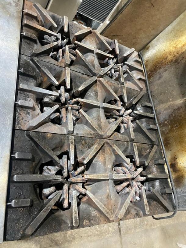 Garland G36-6C stainless steel 6-burner range/oven combo with overhead salamander shelf, back splash, and wired oven rack.