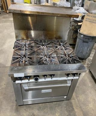 Garland G36-6C stainless steel 6-burner gas range/oven combo with backsplash, salamander shelf, and caster wheels.