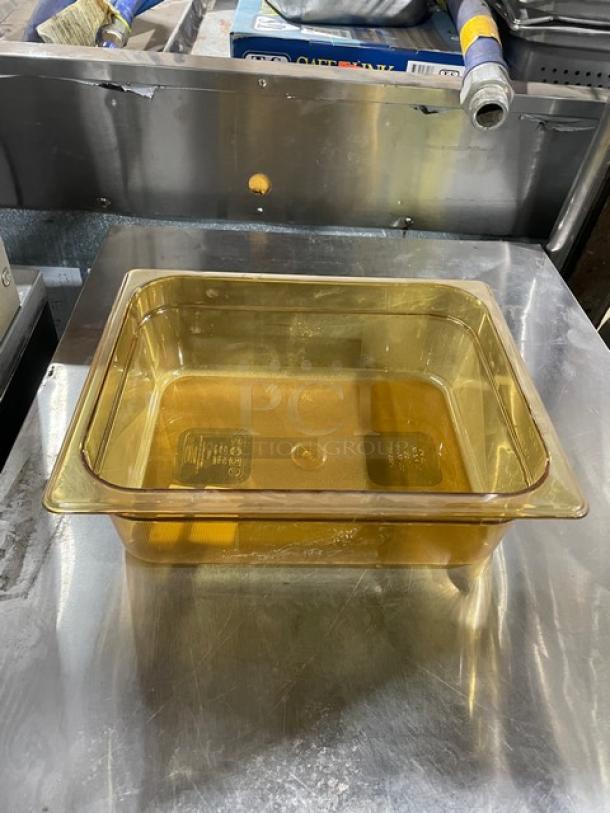 Rubbermaid Commercial Amber High Heat 1/2-Size 4" Deep Food Pan, Model FG224P00AMBR, shown on metal surface, new condition.