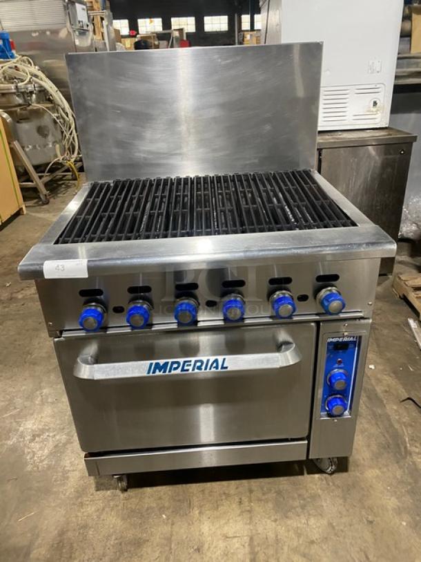 Imperial stainless steel gas-powered char broiler range/oven combo with backsplash, wired rack, on casters, blue knobs.