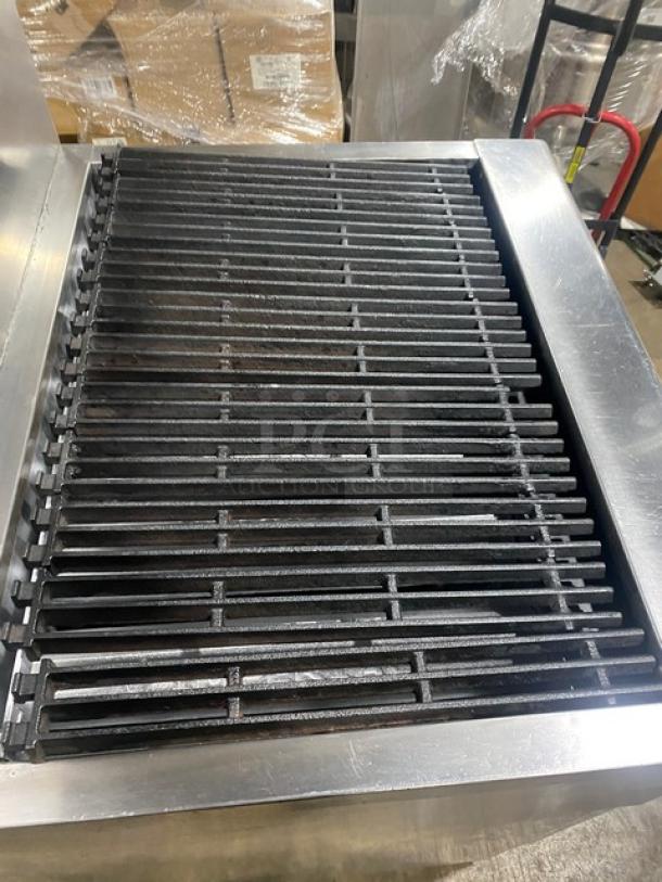 Imperial stainless steel gas-powered radiant char broiler with oven, featuring a backsplash and wired oven rack, on casters.