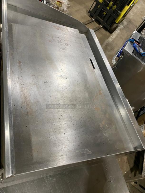 CPG commercial stainless steel gas-powered flat griddle with thermostatic controls, back and side splash. Light wear visible.