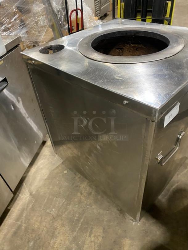 Commercial stainless steel natural gas tandoor oven on casters, featuring a large opening, minor wear, and handle for mobility.
