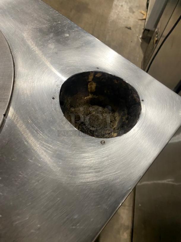 Commercial stainless steel natural gas tandoor oven on casters. Round opening in top; used condition with visible wear.