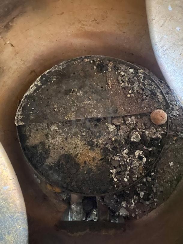 Commercial stainless steel natural gas tandoor oven on casters, interior view, visible wear, features a removable lid.