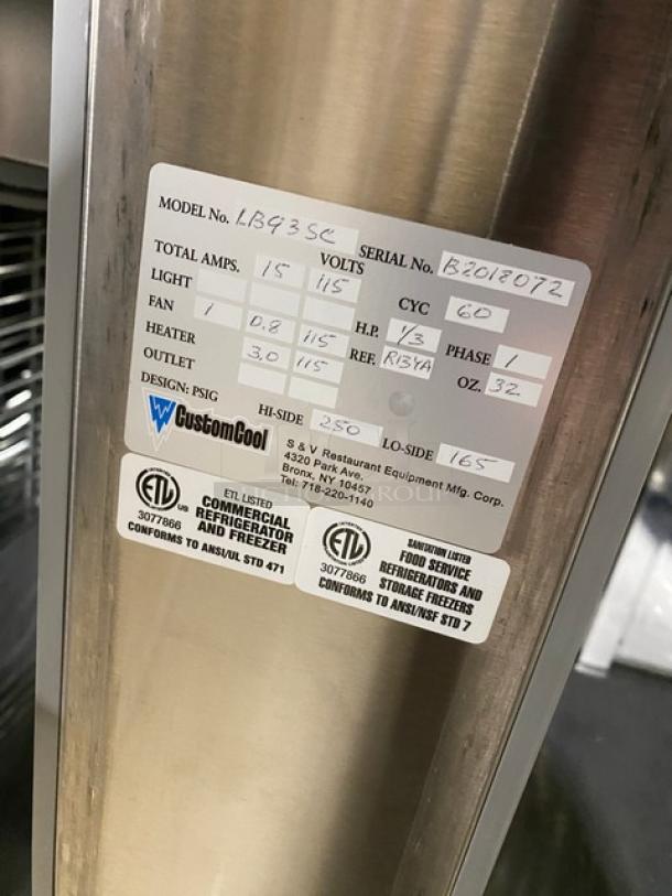 Custom Cool LB93 stainless steel 3-door refrigerated worktop table with up-turned back splash and built-in universal pan rack. Model: LB93, SN: B2018072, 115V 1 Phase, on casters.