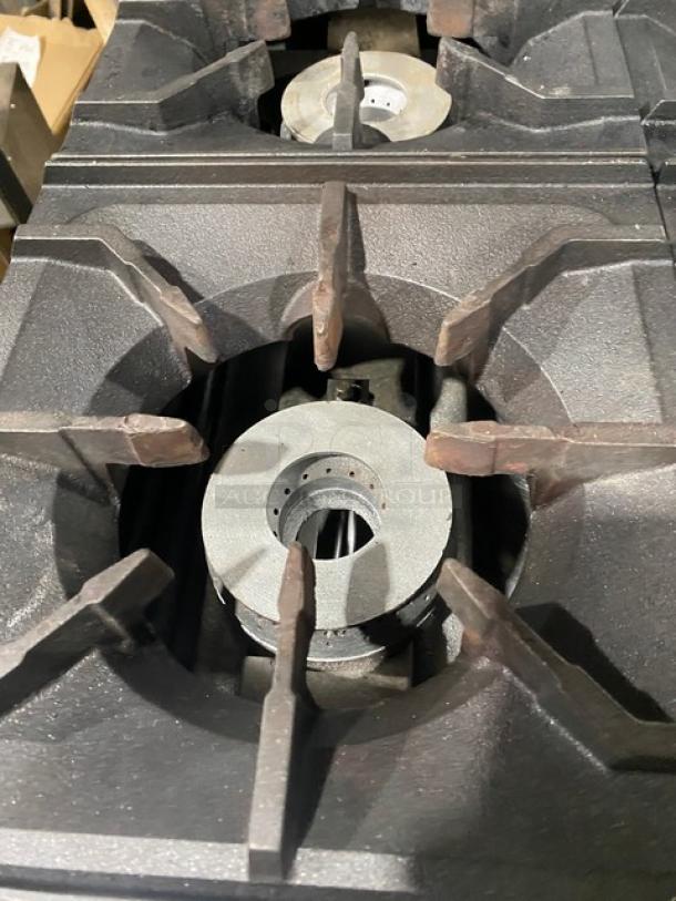 CookRite stainless steel 4-burner gas range with backsplash, overhead salamander shelf, wired oven rack, and casters.