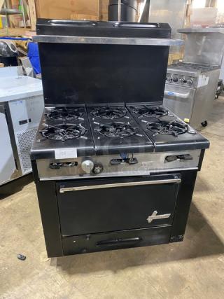 Garland commercial black gas-powered 6-burner range/oven combo with backsplash, overhead salamander shelf, and wired oven rack.