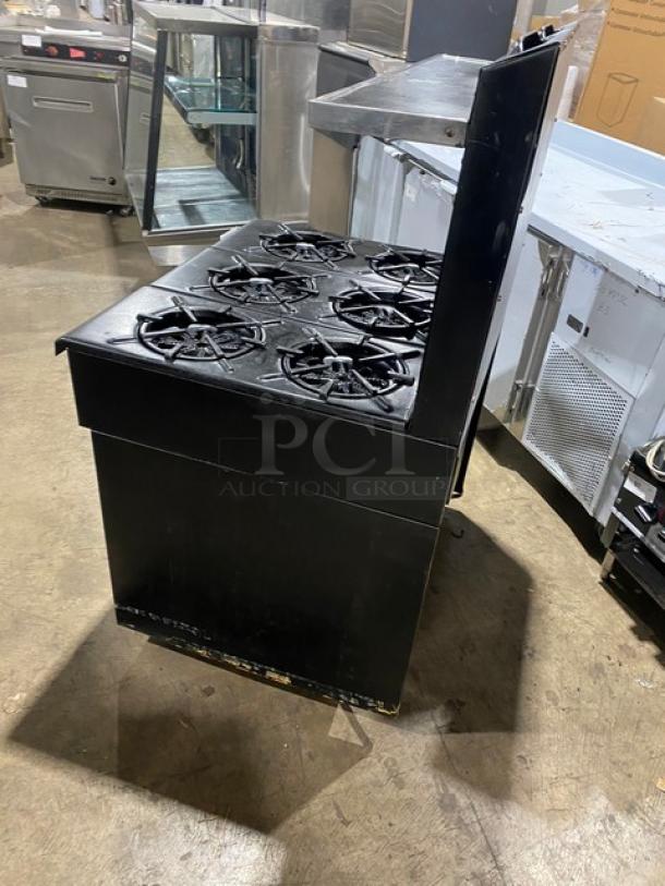 Garland commercial black 6-burner gas range/oven combo with backsplash, overhead salamander shelf, and wired oven rack.