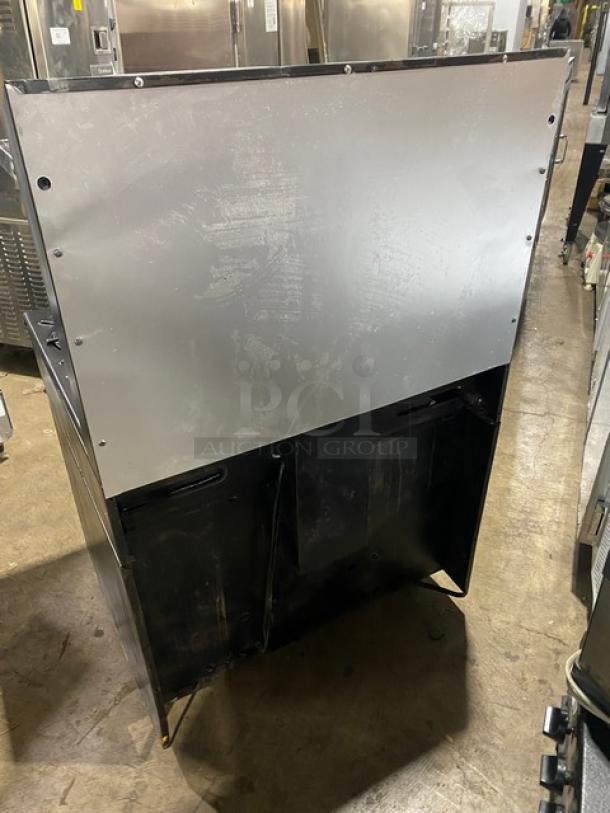 Garland Commercial Black Gas-Powered 6-Burner Range/Oven with backsplash, overhead salamander shelf, and wired oven rack.