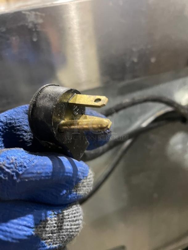 Close-up of a power plug for a Delfield UC4448NA8 refrigerated lowboy. Shown against the stainless steel surface.