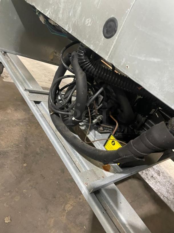 Asber APR49HF commercial fridge underside showing wiring, hoses, and metal frame on casters. Poly coated racks included.