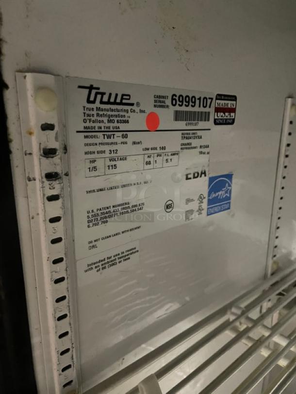 True TWT-60 commercial refrigerator label with serial number 6999107, Energy Star certified, 115V, on poly-coated rack.