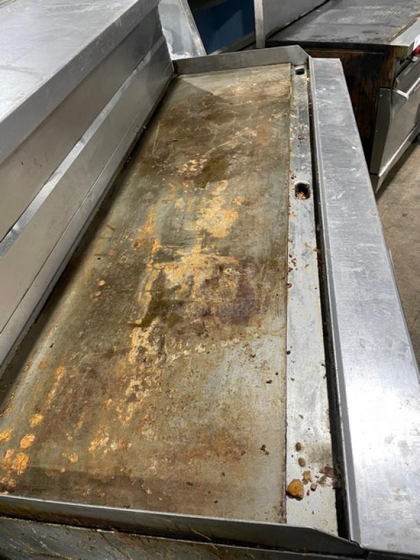 Garland H280 Series stainless steel flat griddle range with double oven, model H289RC72GTH, featuring back and side splash, overhead salamander shelf, and casters. Visible wear on griddle surface.