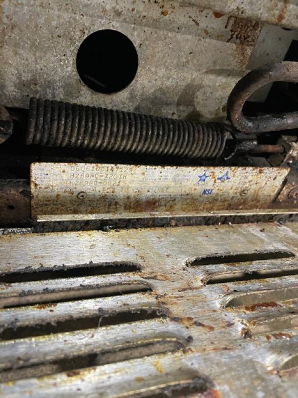 Garland H289RC-72GTH griddle range/oven combo tag with model and serial number. Rust and wear visible on surrounding metal.