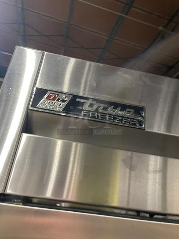 True T-49F-4 commercial stainless steel double-section reach-in freezer, solid half-door, on casters, poly-coated rack, model tag visible.