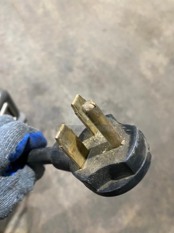 A close-up of a power plug for the 2018 Turbo Chef Rapid Cook Oven, model NGO, showing electrical prongs with visible wear.