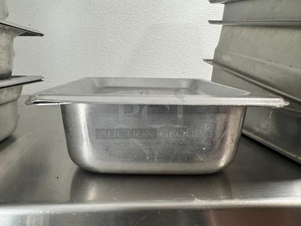 Lot of 2 stainless steel food pans with lids, used condition, visible surface wear, durable for kitchen use.