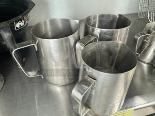 Lot of 3 stainless steel milk frothing pitchers, 20oz each. Used condition with visible wear, sturdy handles.