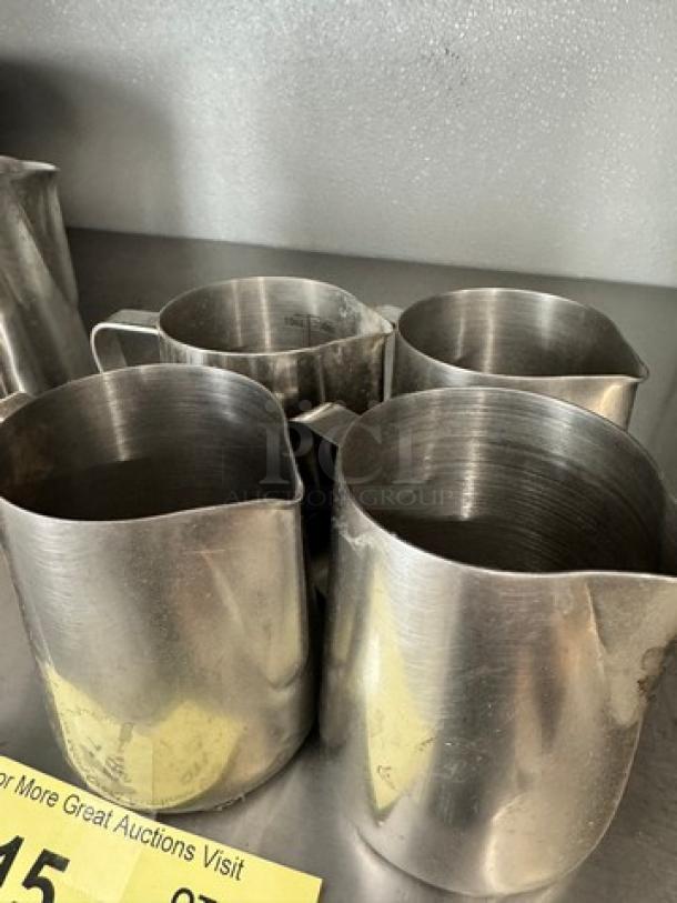 Lot of 4 10oz stainless steel milk frothing pitchers, used condition. Ideal for coffee enthusiasts or baristas.