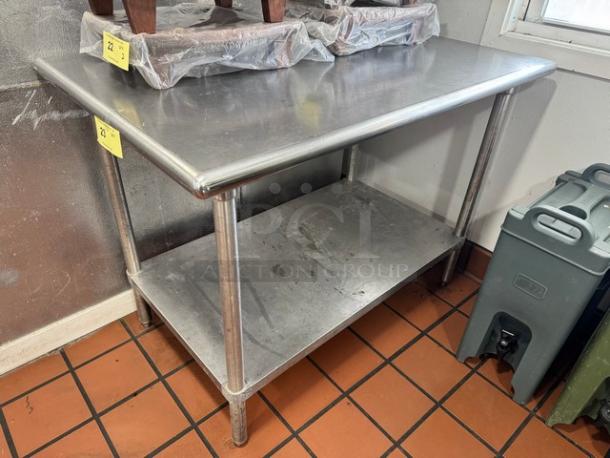 47" stainless steel work table with undershelf, visible wear, sturdy construction, ideal for kitchens or workshops.