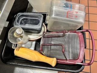 Lot of miscellaneous kitchenware including strainers, measuring cups, storage containers, and utensils in mixed condition.