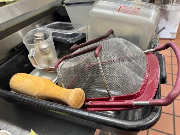 Lot of miscellaneous kitchenware, including metal strainer, wooden pestle, and plastic containers. Used condition.