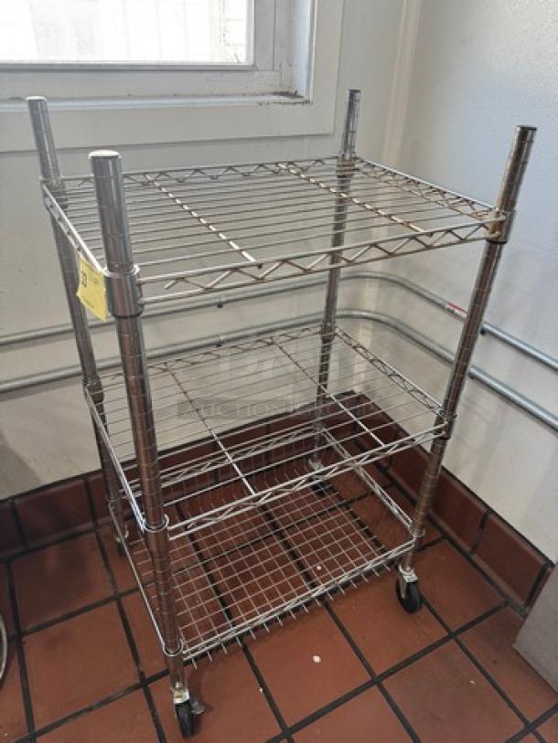 Chrome utility cart with three wire shelves, polished finish, adjustable height, and wheels for mobility. Good condition.