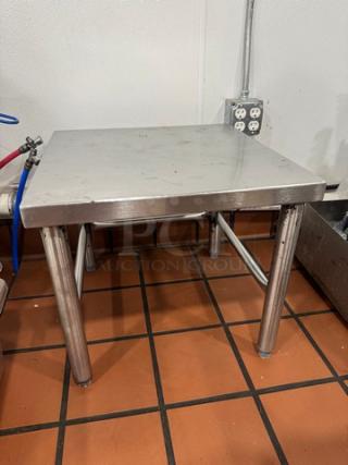 20" stainless steel stand with square top, tubular legs, and welded seams. Slight surface wear; sturdy industrial design.