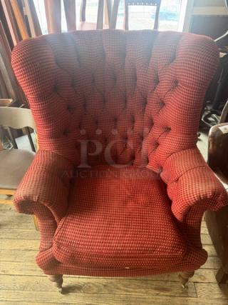 Vintage wingback armchair with red checkered upholstery, tufted back, rolled arms, and wooden legs. Good condition.