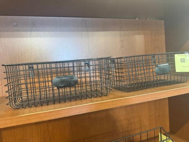 Lot of 2 black metal hanging baskets on wood shelf. Good condition, wire mesh design, with rectangular mounting brackets.