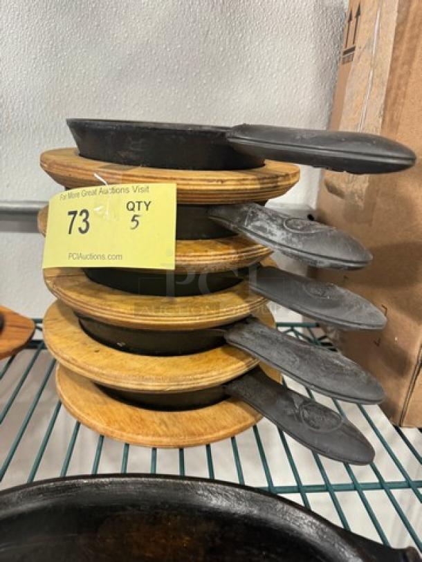 5" cast iron skillets with wooden trivets, model BIDX5, stacked; display tag indicates quantity of five.